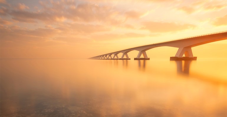 Zeelandbrug tijdens zonsondergang met op de voorgrond de zee