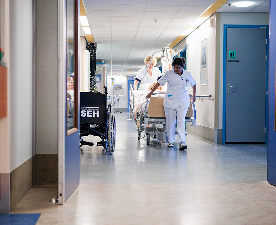 Verzorgende met cliënt op de gang van het woonzorgcentrum WVO  Zorg. Werken in de Zorg en Welzijn sector bied zorgprofessionals volop kansen!