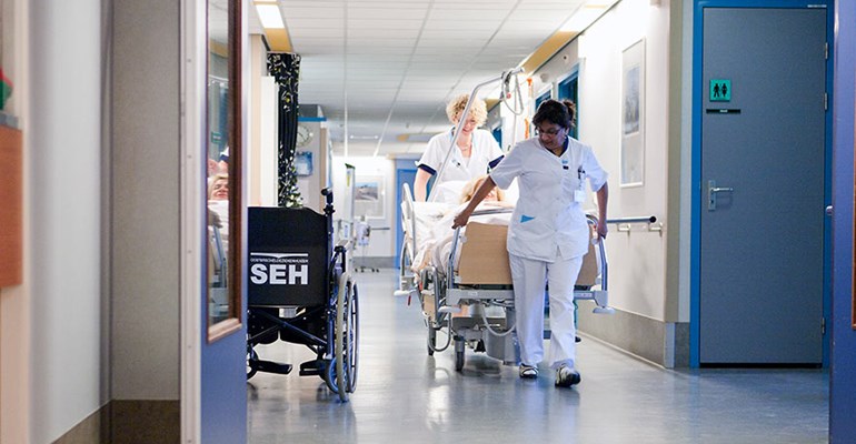 Verzorgende met cliënt op de gang van het woonzorgcentrum WVO  Zorg. Werken in de Zorg en Welzijn sector bied zorgprofessionals volop kansen!