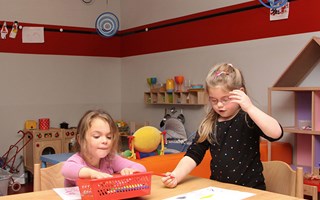 Twee kinderen aan het kleuren aan tafel bij de kinderopvang.